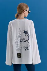 Remerón de manga larga y corte holgado, color blanco, con estampa serigráfica en la espalda que incluye motivos orientales como una rama de flores, un pez koi, una mariposa y texto en japonés. Presenta un parche decorativo en la parte inferior.