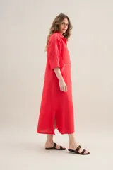 Vestido largo lila de lino, con cuello camisero, mangas cortas, bolsillos frontales con costuras a contratono y aberturas laterales.