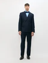 Ambo de doble abotonadura color azul marino, confeccionado en tejido con spandex. Saco de solapas en punta, hombros estructurados y bolsillos con solapa. Pantalón de corte recto con pinza frontal.