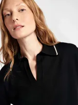 Polo de manga corta confeccionado en tejido de punto, color negro con detalles de líneas en color crema en el cuello, puños y ruedo. Presenta un cuello tipo polo con escote en V.