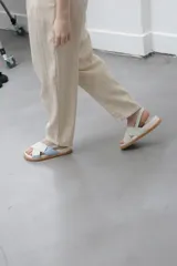 Sandalias planas color celeste y blanco, con tiras anchas cruzadas y suela color caramelo.