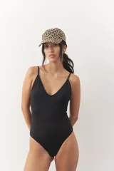 Malla entera de traje de baño color negro, con escote redondo al frente y espalda descubierta con tiras regulables que se atan.