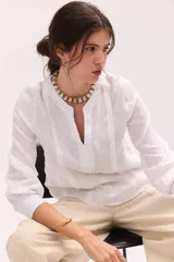 Blusa blanca de lino con escote en V y mangas largas con puños elásticos, combinando delantera estructurada de lino y espalda de algodón con spandex.
