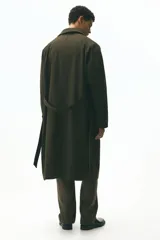 Gabardina estilo Mac de color marrón oscuro, confeccionada en sarga suave. Presenta cuello clásico, cierre frontal con botones ocultos, manga raglán con trabilla y botón en los puños, bolsillos insertados y cinturón extraíble para atar a la cintura. Tiene una abertura en la espalda y forro interior.