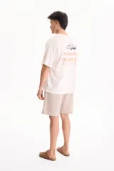 Remera oversize de manga corta color blanco, confeccionada en 100% algodón, con estampado gráfico en la espalda que incluye el texto "Los Angeles, PARADISE CITY" y un dibujo de un auto clásico.