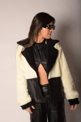 Campera corta de corderito color crema con detalles en cuero sintético negro en cuello, cierre, bolsillos y ruedo.