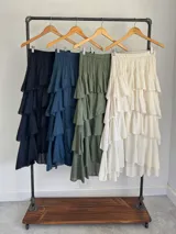 Falda larga color verde militar, confeccionada en algodón, con diseño de múltiples volados escalonados y cintura elastizada.
