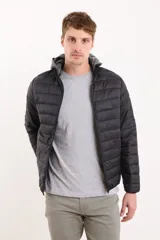 Campera capitoneada negra con capucha de algodón gris desmontable y cierre frontal. Cuenta con dos bolsillos exteriores con cierre.