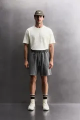 Short tipo jogger de algodón con interior afelpado, cintura elástica ajustable con cordón, bolsillos frontales y bolsillo trasero. Presenta un efecto lavado y estampado gráfico a contraste en el frente.