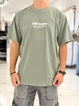 Remera oversize verde militar con cuello redondo y moldería amplia, confeccionada en algodón. Presenta un estampado tipográfico frontal en color blanco con la leyenda "Off-Court Game Set Match Duxon Team".