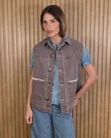 Chaleco de denim 100% algodón en color marrón con efecto lavado, cuello camisero, bolsillos frontales con solapa, cierre de botones y costuras decorativas en contraste de color blanco.