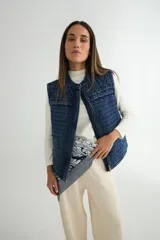 Chaleco de denim acolchado con efecto lavado, diseño sin mangas, cierre frontal y bolsillos laterales.