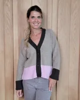 Cardigan de punto con escote en V y cierre frontal de botones. Presenta un diseño tricolor con cuerpo en beige, detalle de franja inferior en rosa y terminaciones en puños, cuello y tapeta de botones en color marrón oscuro.