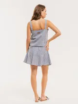 Falda corta color beige con rayas verticales blancas, corte evasé y volado en el ruedo.