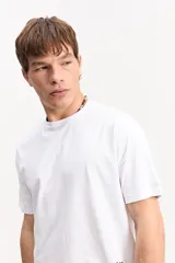 Remera blanca de manga corta, confeccionada en mezcla de algodón y poliéster, con diseño liso al frente y estampa en la espalda.