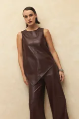 Top sin mangas de símil cuero color marrón oscuro, con escote redondo y diseño asimétrico en el ruedo inferior.