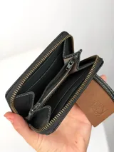 Mini billetera de cuero con textura efecto cocodrilo y cierre perimetral. Presenta un parche central con el logo de la marca grabado.