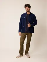 Campera de estilo safari en color azul marino, confeccionada en algodón. Presenta cuello alto, cierre frontal con cremallera y cuatro bolsillos delanteros con solapa y botones metálicos.