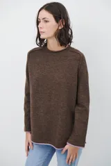 Buzo de tejido de punto color beige, con corte relajado, cuello redondo y mangas largas. Presenta detalles de terminaciones en color azul marino en los puños y en el ruedo inferior.