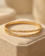 Pulsera esclava de acero con baño de oro, compuesta por una hilera de circonias engarzadas en bisel.