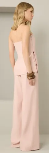 Conjunto de dos piezas en color rosado, compuesto por un top strapless con cierre lateral y un pantalón de corte recto. El top presenta un diseño estructurado y minimalista.