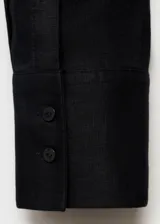Camisa de lino color negro, de diseño oversize, con cuello camisero, cierre frontal de botones y manga larga con puños abotonados.