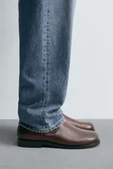 Bota de caña media fabricada en piel color marrón oscuro, con cierre de cremallera lateral, horma cuadrada y suela con ligero tacón.