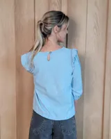 Blusa blanca de algodón tussor, con cuello redondo, mangas 3/4 abullonadas y detalle de volados en los hombros.