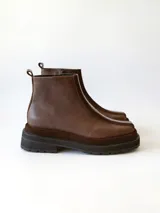 Bota corta de cuero en tonos chocolate, con diseño de paneles texturizados y suela track robusta de goma.