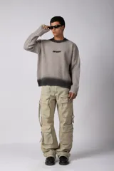 Sweater de punto acanalado con diseño degradado de negro a gris en el cuello y el ruedo. Presenta un corte regular y un pequeño bordado central en el pecho.