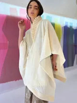 Ruana color crudo tejida en lana merino con cuello plisado a mano y terminaciones en fieltro de lana.