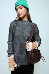 Sweater de punto con hilo de lurex brillante, color azul con rayas verticales en verde. Presenta cuello redondo, mangas largas con puños de piel sintética negra y corte holgado.