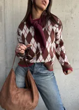 Sweater de tejido de punto con diseño de rombos en tonos chocolate, blanco y detalles en bordó. Presenta cuello redondo, mangas largas y terminaciones acanaladas en puños y ruedo.