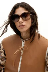 Chaleco reversible de gamulán de oveja en color natural, con corte holgado, cuello a la base y terminaciones al corte. Presenta tiras de cuero en el frente para atar.