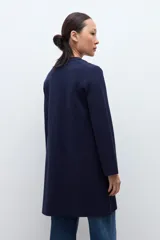 Sacón azul marino de corte largo, con cuello solapa, cierre frontal de dos botones dorados y bolsillos de parche.
