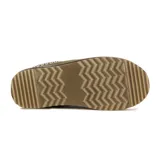 Pantufla tipo zueco de cuero gamuzado color verde oliva, con interior de peluche y suela de plataforma de goma color beige. Presenta un detalle de costura decorativa trenzada en el borde superior.