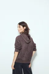 Buzo canguro color marrón oscuro con efecto lavado, calce relajado, capucha integrada, bolsillo frontal tipo canguro y terminaciones clásicas en puños y ruedo.