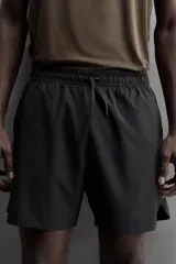 Pantalón corto deportivo color marrón oliva, confeccionado en tejido técnico ligero y elástico, con forro interior. Presenta cintura elástica ajustable con cordón, bolsillos frontales, bolsillo de seguridad trasero con cierre y aberturas laterales en el bajo.