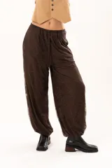 Pantalón tipo babucha de encaje color chocolate, con forro interior, cintura regulable y elásticos en los tobillos que generan una silueta abuchonada.