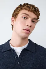 Suéter de punto suave color azul marino, con cuello polo y cierre frontal de tres botones.