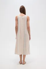 Vestido midi sin mangas de lino y algodón, color beige con rayas verticales blancas y negras, corte holgado y cuello a la base.