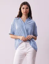 Blusa celeste y blanca a rayas verticales, con cuello con solapa y escote en V. Delantera cruzada con abertura simulada y mangas cortas.