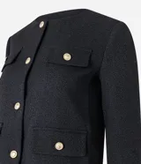 Chaqueta de manga larga confeccionada en tejido tweed color negro, con cuello redondo, cierre frontal mediante botones metalizados dorados y bolsillos frontales con solapa y botones a juego.