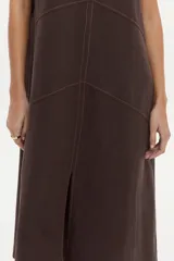 Vestido midi de corte recto y color marrón camel, con cuello redondo, sin mangas y costuras pespuntadas visibles con diseño geométrico en el frente.