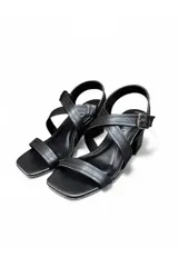 Sandalias de taco cuadrado y punta cuadrada color negro, con tiras cruzadas en el empeine y cierre de hebilla en el tobillo.