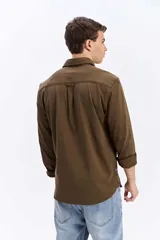 Camisa de manga larga color verde militar, con cuello tradicional y cierre frontal de botones.