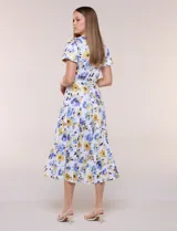 Vestido midi de seda fría blanca con estampado floral en tonos azules y amarillos, escote en V con cuello solapa, mangas cortas, lazo ajustable en la cintura y falda plisada.