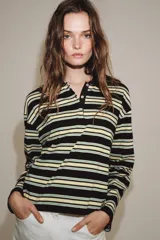 Polo de manga larga confeccionado en algodón, con diseño a rayas horizontales en tonos amarillos, verdes y oscuros. Presenta cuello solapa, cierre frontal con botones y bajo recto.