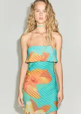 Vestido corto de viscosa con diseño entallado, escote palabra de honor con solapa vuelta y tirantes finos multiposición que se atan al cuello. Presenta un estampado floral sobre fondo turquesa con rayas diagonales y cuenta con forro interior.