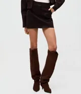 Short pollera de gamuza sintética color marrón, con cintura estructurada, botón forrado y bolsillos delanteros funcionales.